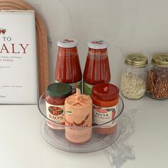 some jars of sauce and other condiments are sitting on a counter next to a sign