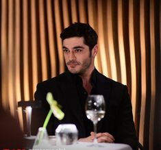 a man sitting at a table with a glass of wine