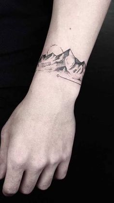 a person's hand with a mountain tattoo on the left side of their arm