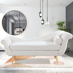 a white couch sitting in front of a round mirror