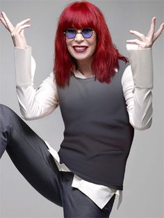 a woman with red hair and glasses is jumping in the air