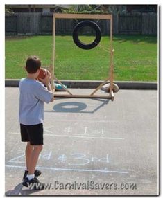 a young boy is playing with a swing set in the yard at an outdoor basketball court