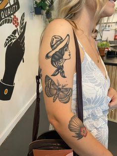 a woman with a hat and butterfly tattoo on her arm holding a brown handbag