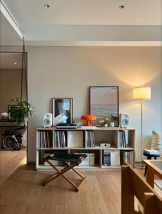 a living room filled with furniture and bookshelves next to a lamp on top of a hard wood floor