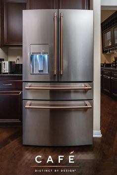 a metallic refrigerator freezer sitting in a kitchen next to brown cabinets and wooden floors