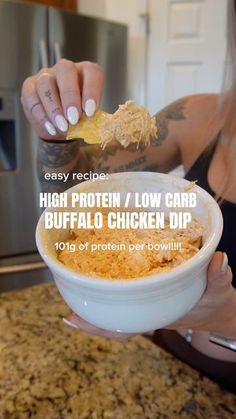 a woman holding a bowl of food in her hand with the words high protein low carb buffalo chicken dip