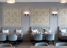 a restaurant with blue chairs and tables in front of two wall mounted windows that have stone tiles on them