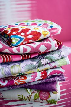 a stack of cloths sitting on top of a pink tablecloth covered in flowers