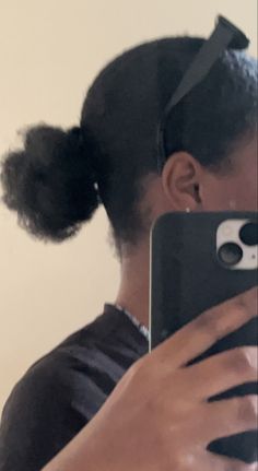 a woman taking a selfie in front of a mirror with her hair styled into a pony tail