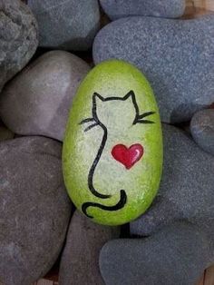 a painted rock with a cat's face on it and a heart in the middle