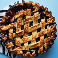 a blueberry pie with latticed crust is on top of a black and white napkin