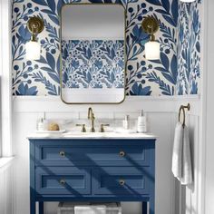 a bathroom with blue and white wallpaper on the walls, two sinks and a mirror