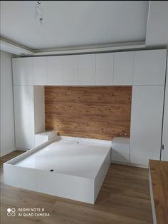 an empty bed in a room with white walls and wood flooring on the wall