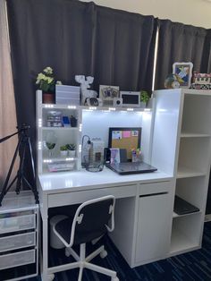 a white desk with a laptop computer on top of it next to a shelf filled with other items