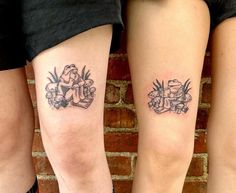 two people with tattoos on their legs standing in front of a brick wall and holding onto each other