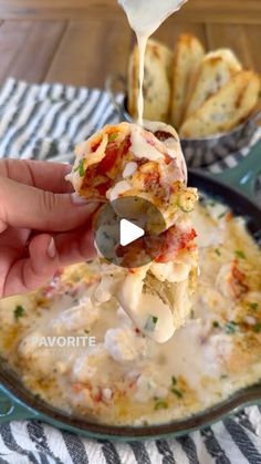 someone is dipping some food into a skillet with cheese and other toppings on it