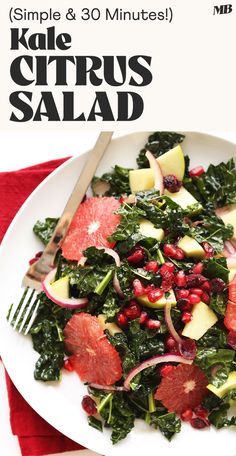 a white plate topped with kale and citrus salad next to a red napkin on top of a wooden table