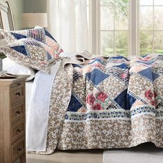 a bed covered in a quilt next to a window