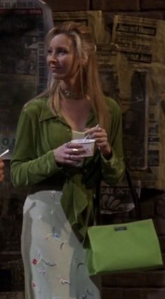 a woman in a green shirt is holding a cup