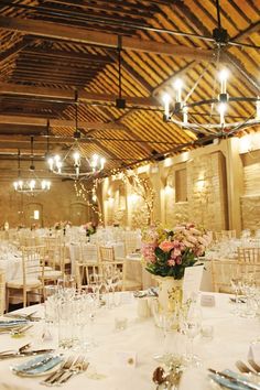 the tables are set for an event with white linens and floral centerpieces