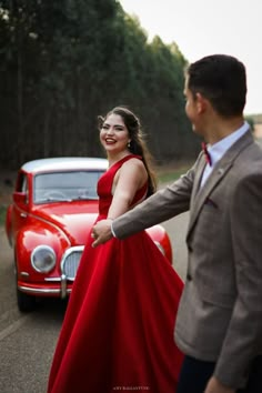 a woman in a red dress standing next to a man