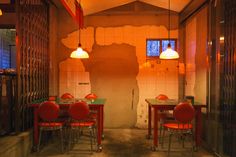 an empty restaurant with red chairs and tables in front of a wall that has been torn down