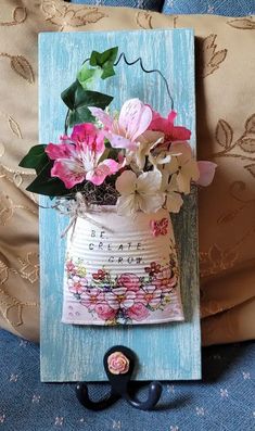 a vase with flowers is hanging on a blue frame next to a pair of black handles