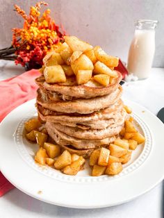 a stack of pancakes sitting on top of a white plate next to a glass of milk