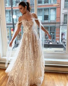 a woman standing in front of a window wearing a dress