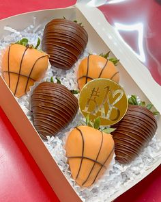 four chocolate covered strawberries in a box with a gold medal on the top one