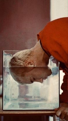 a woman looking at a glass with water in it's mouth and the reflection of her face