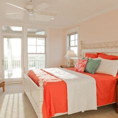 a bedroom with orange and white bedding, two chairs and a window in the corner