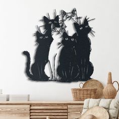 two black cats sitting next to each other in front of a wall mounted art piece