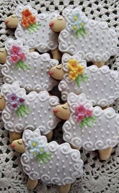 decorated cookies are arranged in the shape of sheeps with flowers on their heads and tails