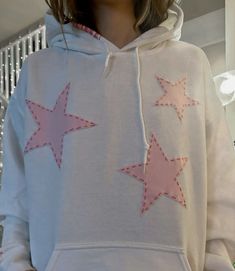 a woman wearing a white hoodie with pink stars on it