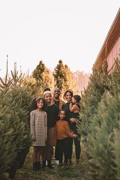 a group of people standing next to each other in front of trees at a christmas tree farm