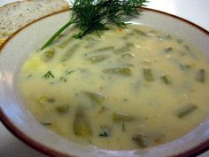 a white bowl filled with soup next to a slice of bread on top of a table