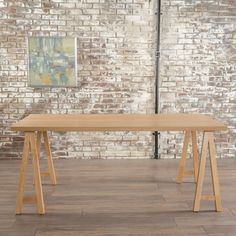 a wooden table sitting on top of a hard wood floor next to a brick wall