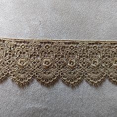 an image of a gold lace trim on a white cloth with flowers and leaves in the center