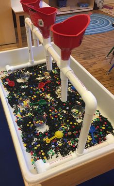 two red buckets sitting on top of a table filled with sprinkles