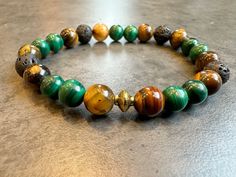 Introducing our top-selling Earthstone Fusion Bracelet: Lava Stone, Tiger's Eye, and Malachite Jewelry. Handcrafted with meticulous attention to detail, this unique bracelet combines the powerful properties of Lava Stone, Tiger's Eye, and Malachite beads. Lava Stone brings grounding and strength, while Tiger's Eye promotes balance and mental clarity. The mesmerizing green tones of Malachite symbolize growth and transformation. This versatile Earthstone Fusion Bracelet is perfect for any occasion Moss Agate Bracelet, Art Bracelet, Malachite Bracelet, Obsidian Bracelet, Lava Stone Bracelet, Malachite Jewelry, Hippie Bracelets, Onyx Bracelet, Natural Stone Bracelets