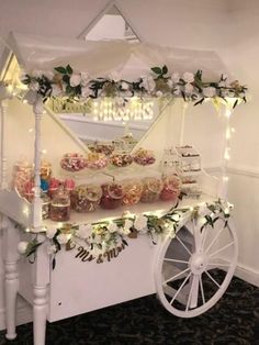 a white cart filled with lots of food on top of a floor next to a wall