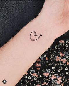 a small heart tattoo on the left inner arm, with an arrow in the middle