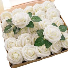 a box filled with lots of white roses and green leaves on top of each other