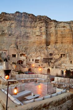 an outdoor hot tub in front of a rocky cliff with lit candles on the side