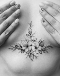 a woman's chest with flowers and leaves tattooed on the side by her hands