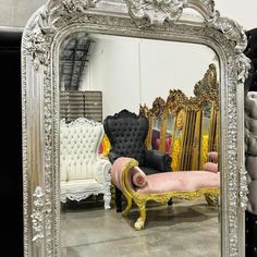 an ornate silver framed mirror sitting on top of a floor next to couches and chairs