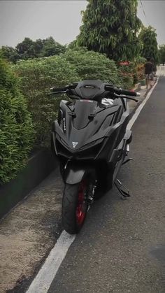 the motorcycle is parked on the side of the road next to some bushes and trees