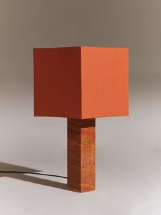 an orange lamp with a red square on it's base and a black cord