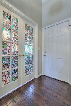 an empty room with stained glass doors and wood floors in front of a white door